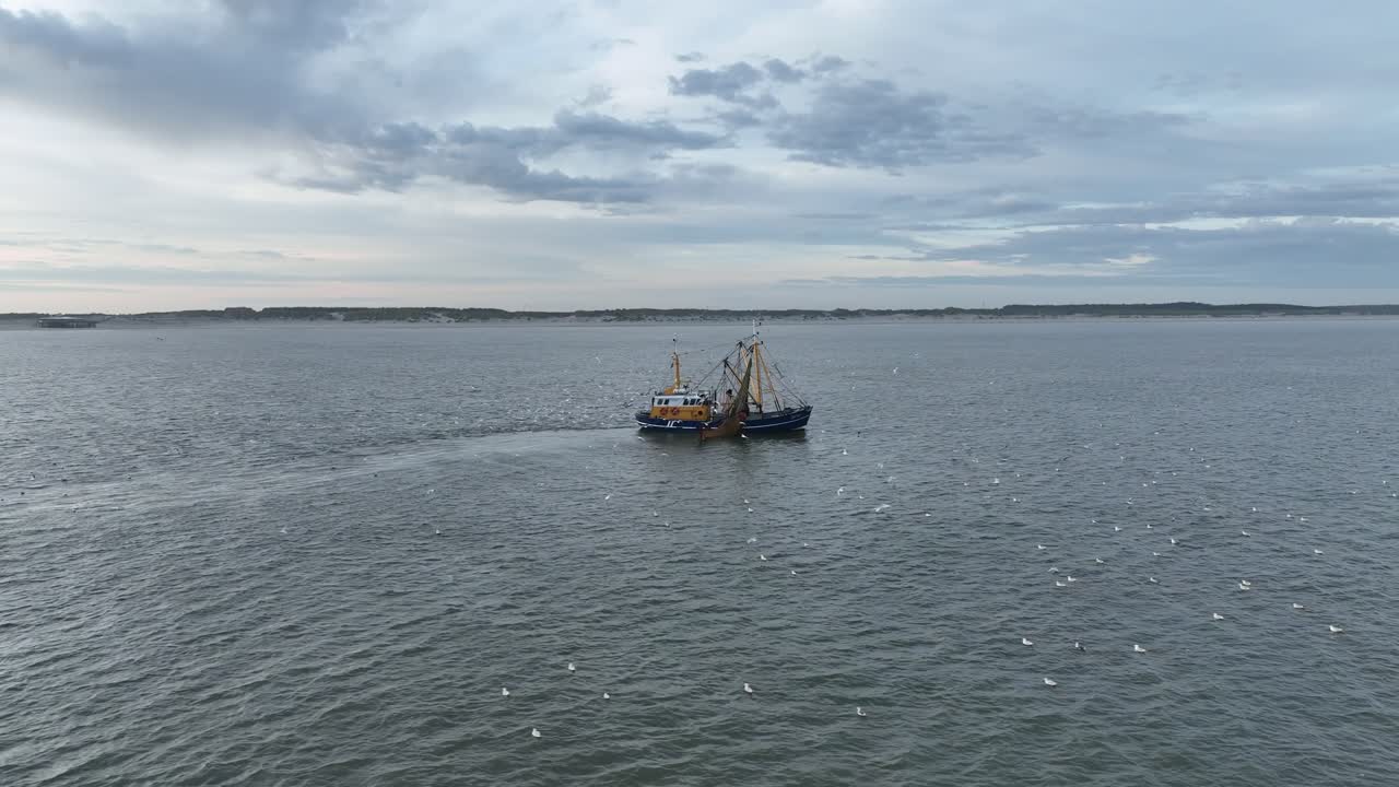 아멜랜드 해안의 물속에서 그물을 끌고 다니는 어부 배의 드론 촬영