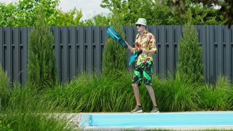 man juggling flippers by the pool