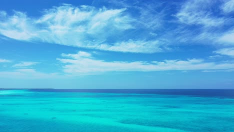 Colores-Vivos-De-Papel-Tapiz-Marino-Con-Nubes-Congeladas-En-Un-Cielo-Azul-Brillante-Sobre-El-Horizonte-Oceánico-Y-Una-Laguna-Turquesa-Brillante-En-Antigua,-Espacio-De-Copia