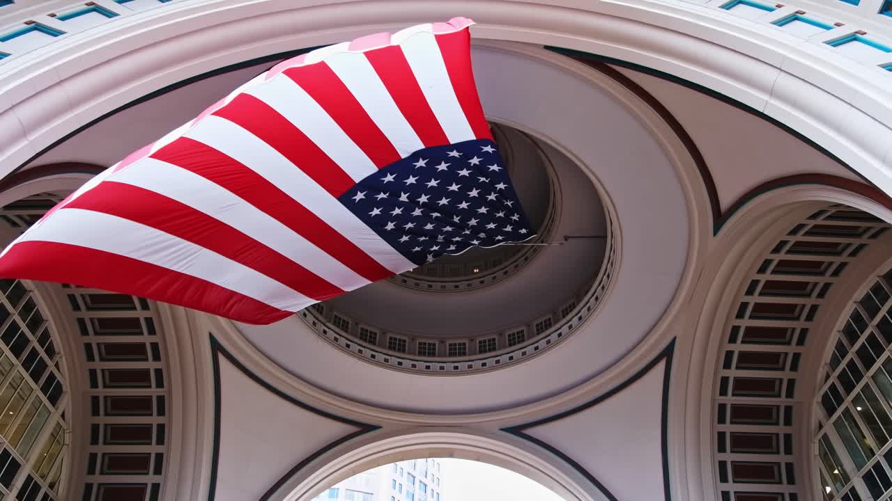 American flag is blown in Rowes Wharf in daylight. Bottom view. Tall buildings in background. Boston, Massachusetts, USA
