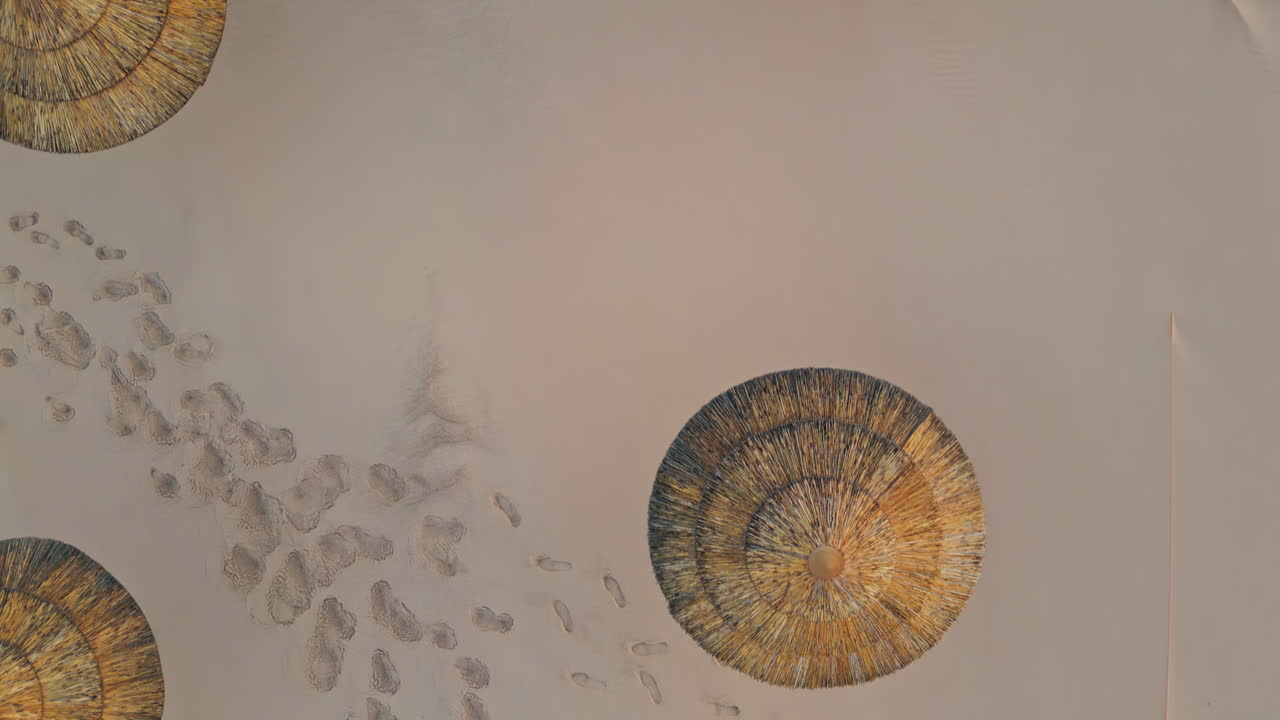 Straw umbrellas footprints desert top view. Aerial sandy surface with parasols