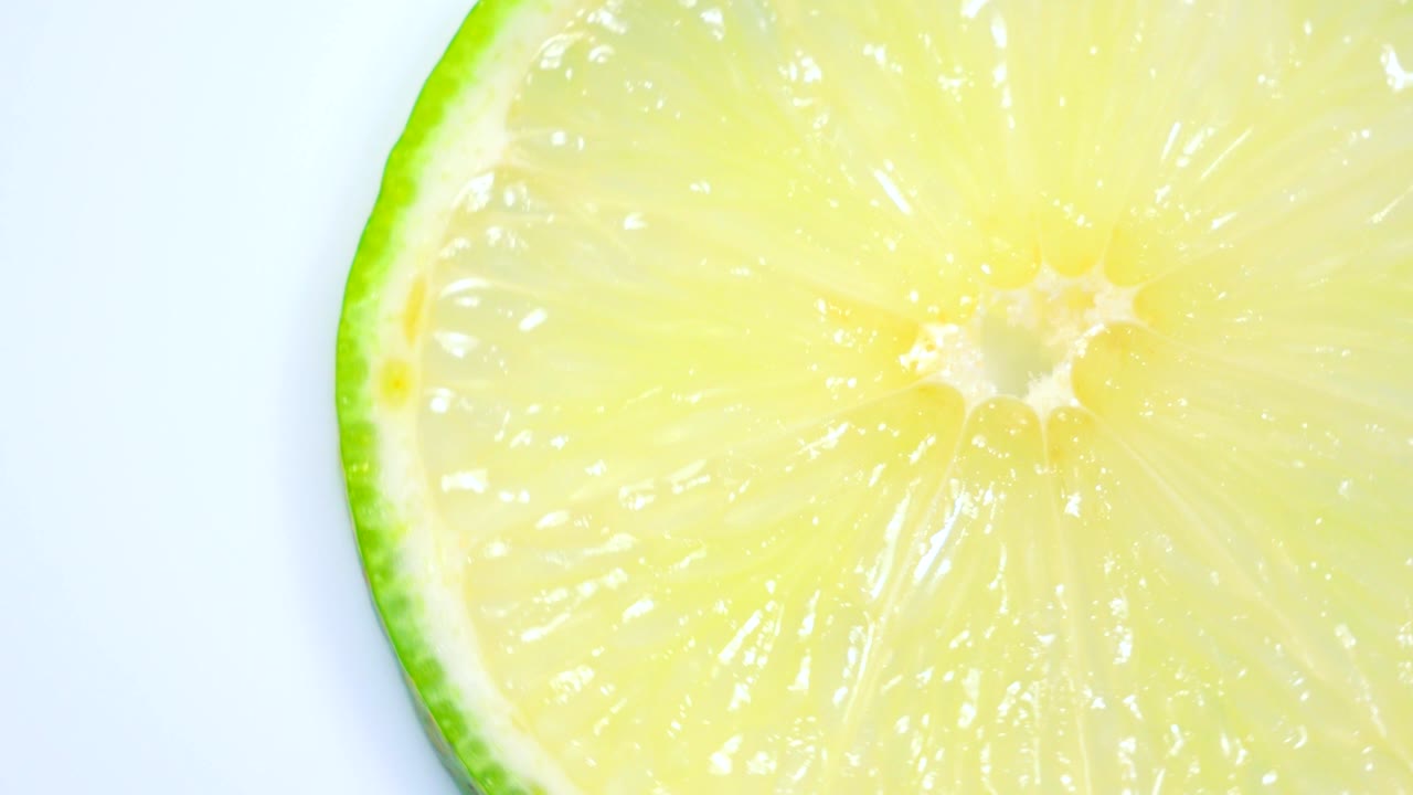 신선한 녹색 레몬 슬라이스는 세부 사항과 함께 스튜디오에서 천천히 회전하고 있습니다.