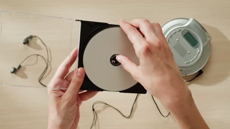 hands holding a cd and a cd player