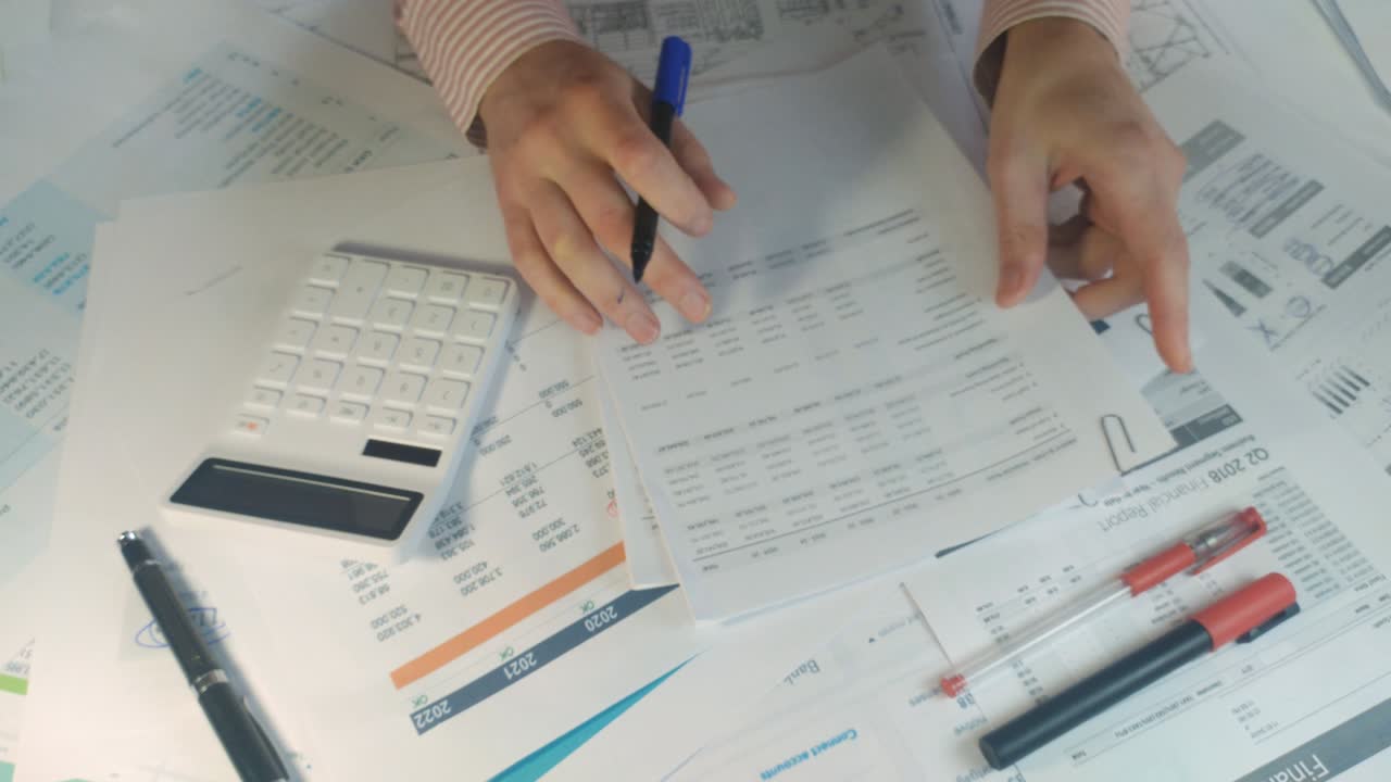 empresario cuenta en la calculadora y escribe los datos en el lugar de trabajo