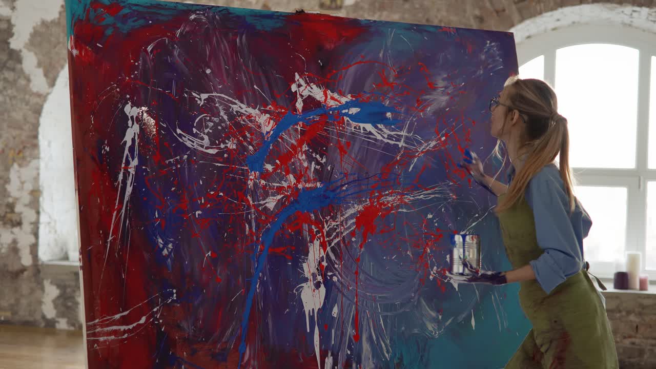 mujer trabaja en la pintura abstracta, salpica pinturas en el lienzo emocionalmente