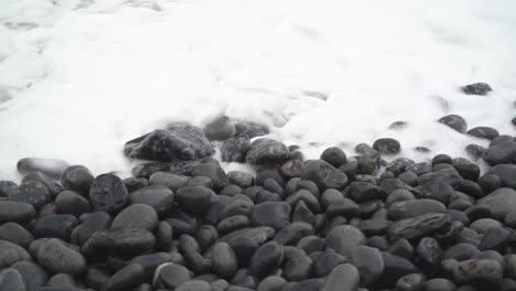 panorámica hacia abajo después de que la marea invernal salpique en una playa rocosa en la bahía de dunraven, gales del sur