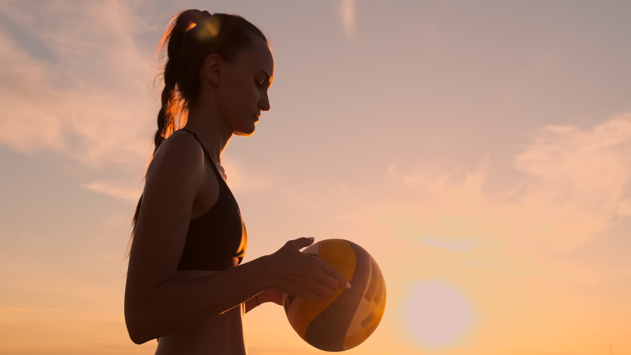 젊은 소녀가 해변에서 볼리볼을 뛰고 느린 동작을 합니다.