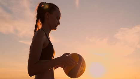 una joven salta y sirve voleibol en la playa en cámara lenta.