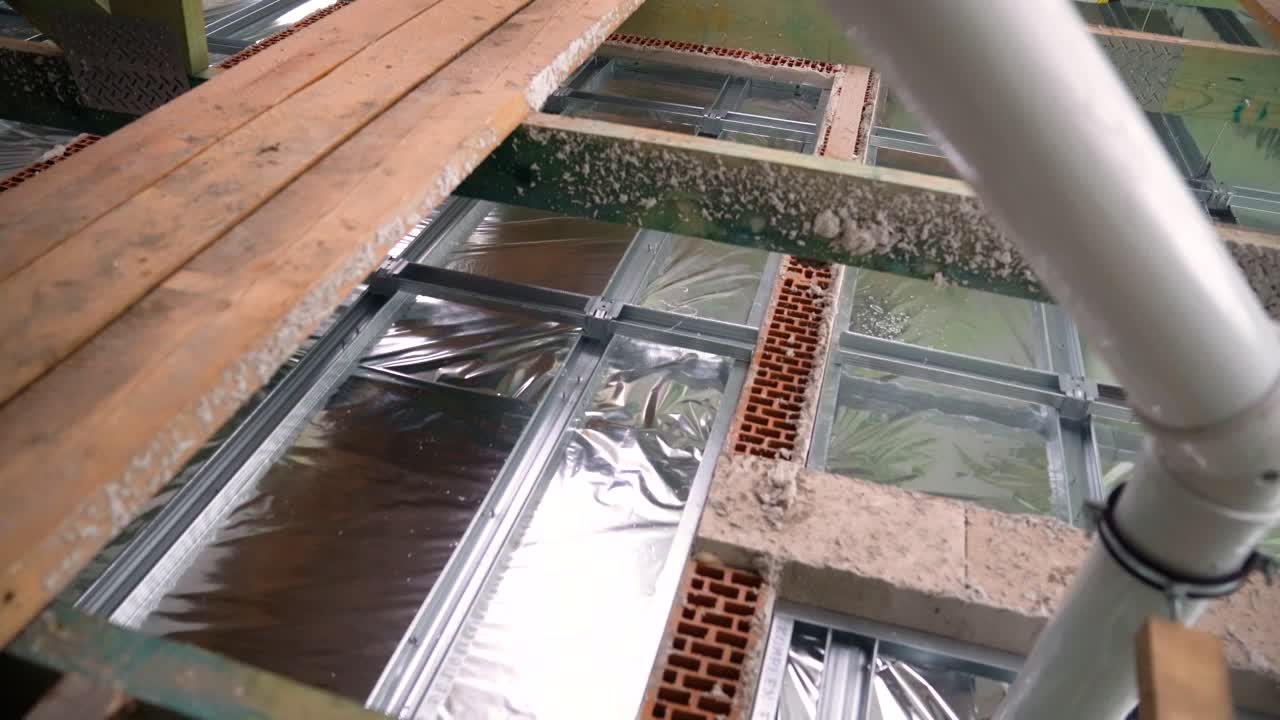 Exposed insulation over floor framing under construction in attic