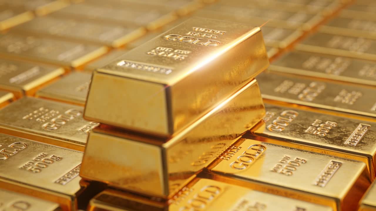 Calare il lingotto d'oro superiore su una coppia impilata su un piano, mostrando i punzoni stampati per una conservazione sicura