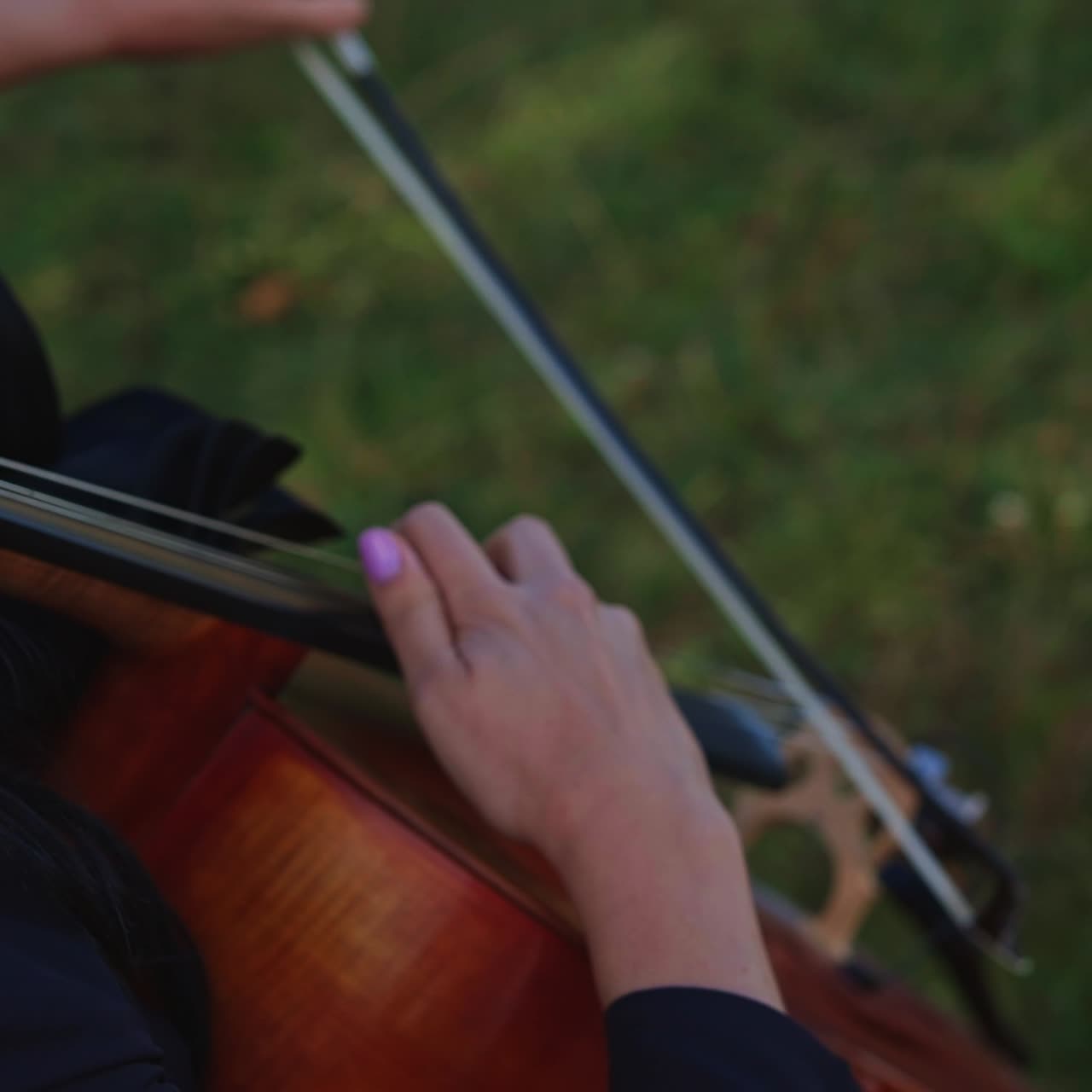 Young pretty violinist playing on nature. Perfomance of musician plays the cello
