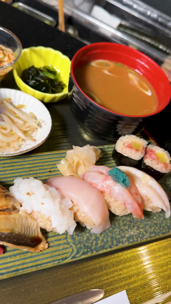 サラダ、副菜、味噌汁が添えられた盛り合わせ寿司の回転するクローズアップ
