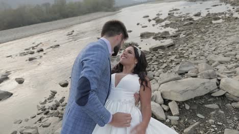 Wedding-couple-standing-near-mountain-river.-Groom-and-bride-in-love