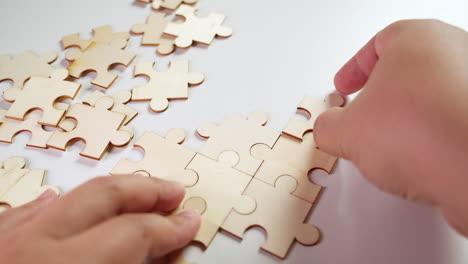 a person trying to solve a jigsaw puzzle without pictures, hand holding the pieces in place while the right hand adds one piece after another