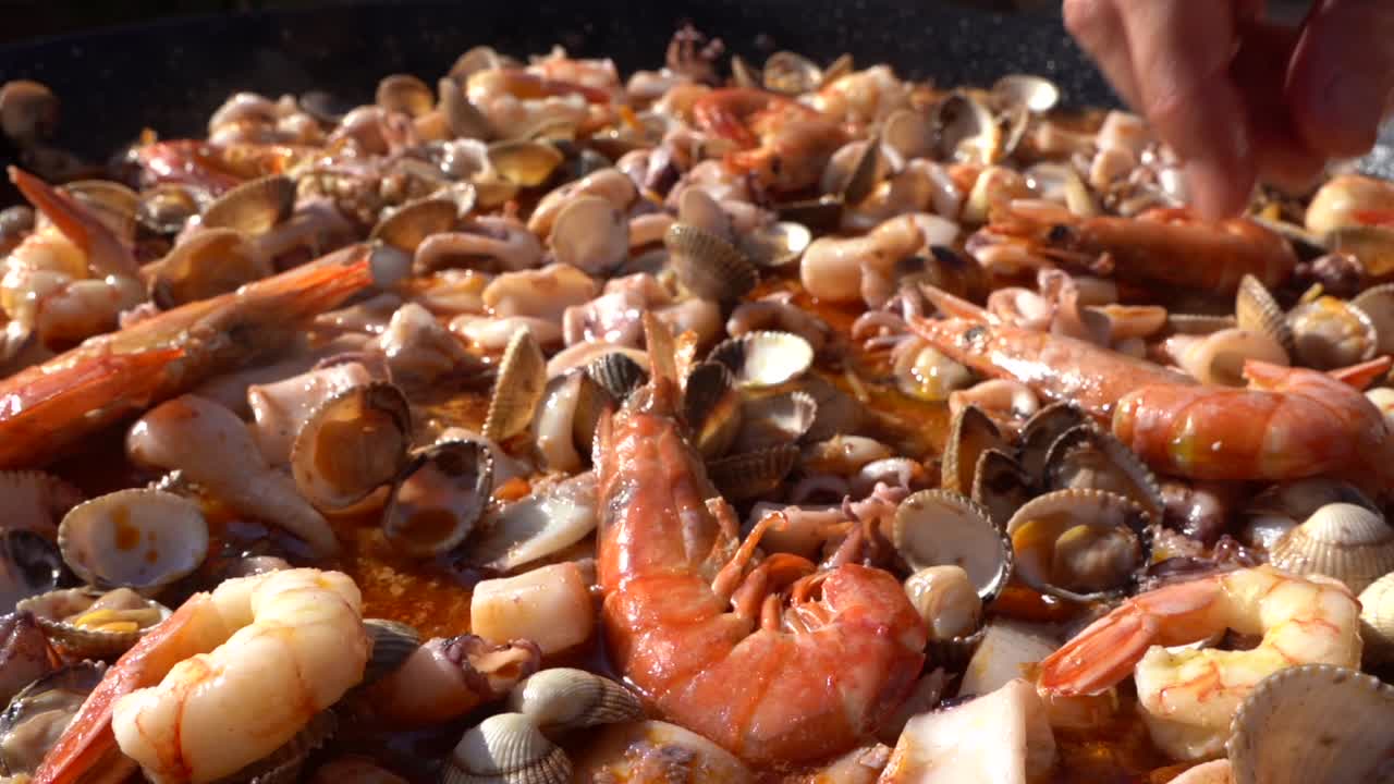 dando los toques finales a la paella, decorando con grandes suculentas gambas por encima