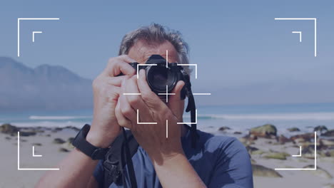 camera user interface frame and focus screen over caucasian senior man by the sea taking photos