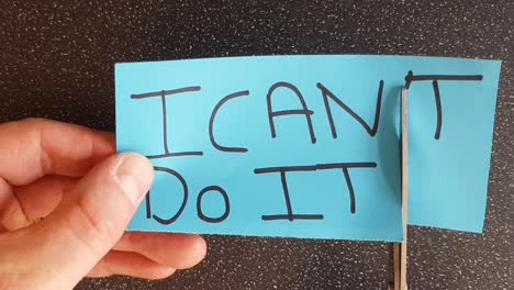 man using scissors to remove the t from the word can't t leaving the positive motivational part. i can do it