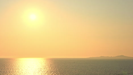 A-golden-sun-hangs-over-a-golden-ocean-and-island-mountains