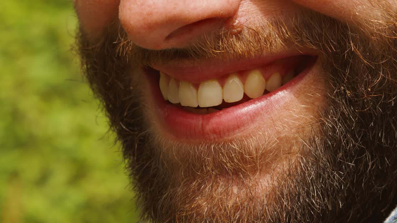 cerca de la cara de un hombre barbudo con dientes blancos sonrientes aislados