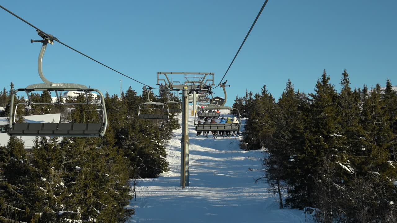 View from ski chairlift, in slow motion. People going up mountain in winter resort