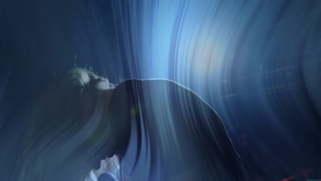 woman bending forward on dark studio stage, featuring swirling blue lights showing technology theme