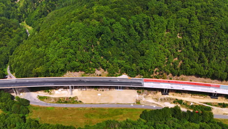 freeway is being constructed over the highway. traffic system in the stunning mountains covered with woods. aerial view