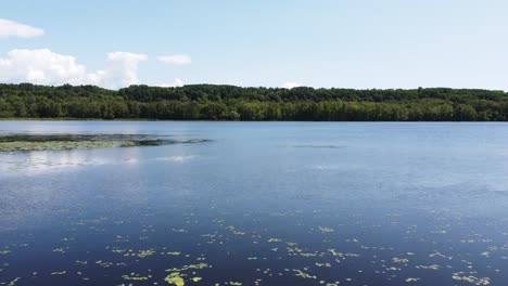 aerial flyover natural cottage lake in quebec during sunny day with forest in background