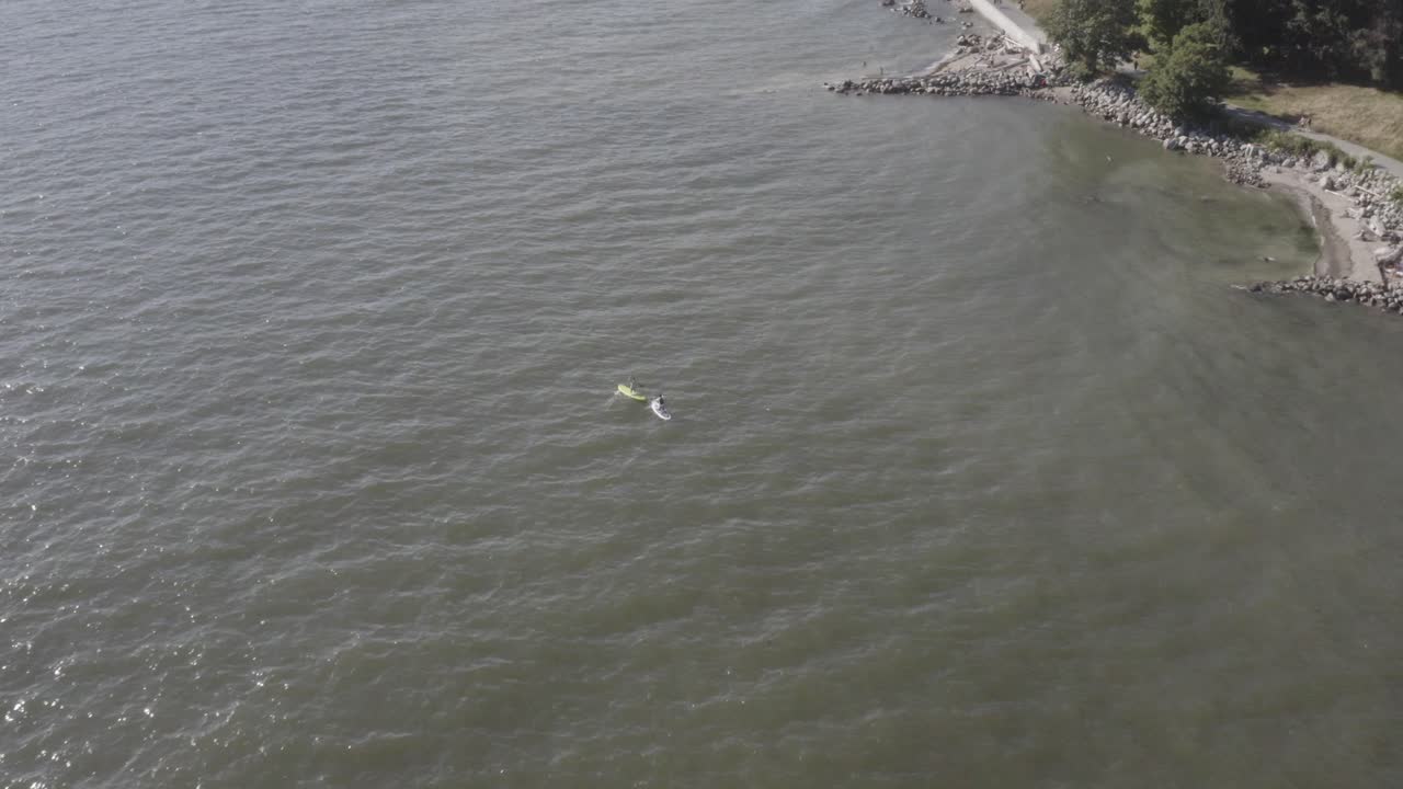 덥고 화창한 날 커플 패들 보딩 위를 공중 비행하며 웨트 스위트가 바다에서 낭만적인 파도를 만들면서 얕은 끝에 가까운 해변 공원 옆 바다에 앉아 있습니다. 1-2