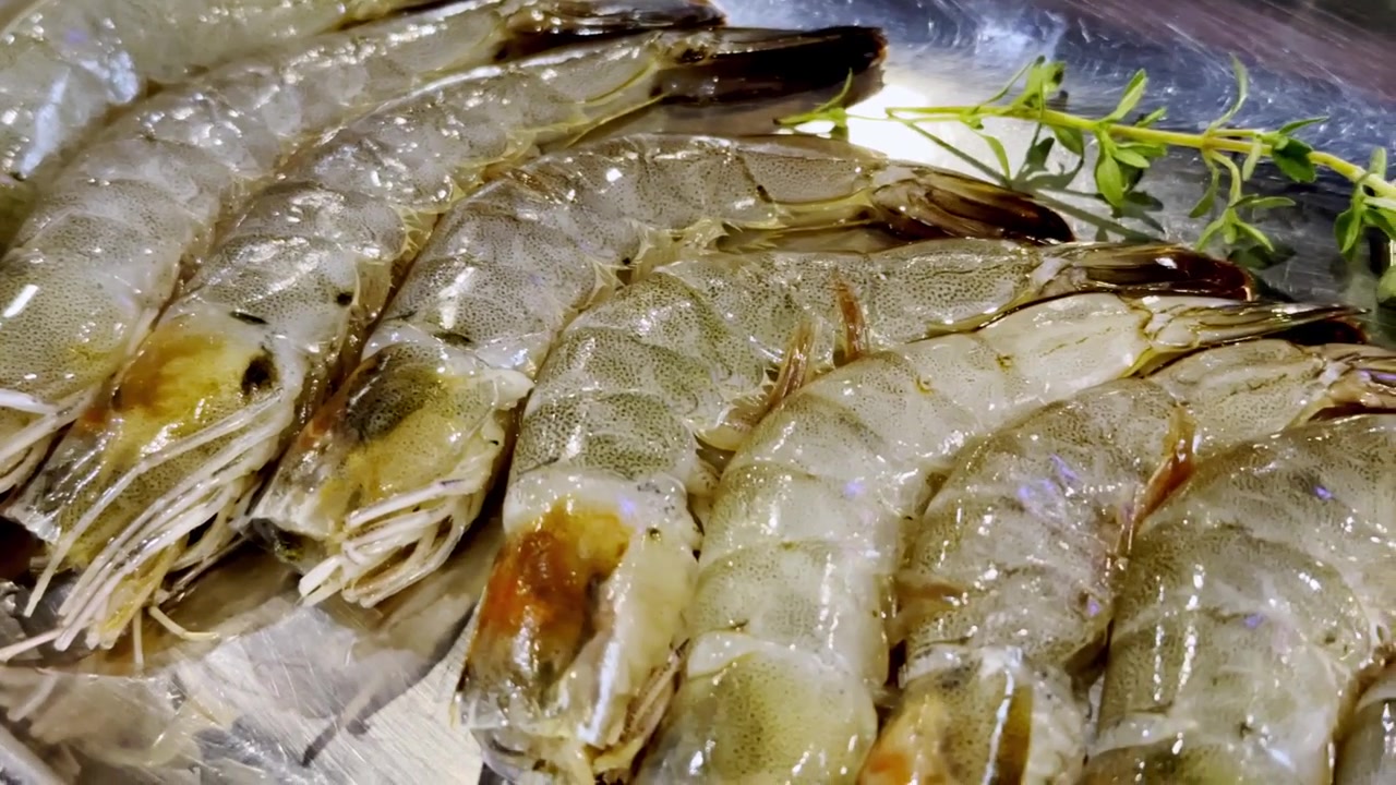Close-up of fresh shrimp sizzling on a hot barbecue pan, capturing juicy seafood, rising steam, and delicious grilled flavors in a cooking scene.