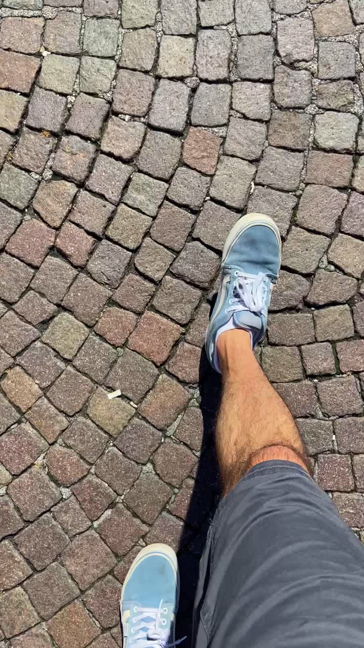 Point of view shot of man in first person walking on cobble stone floor in streets of European city. Old historic center or town square. Tourist visiting landmarks. Walking shoes daily commute by foot