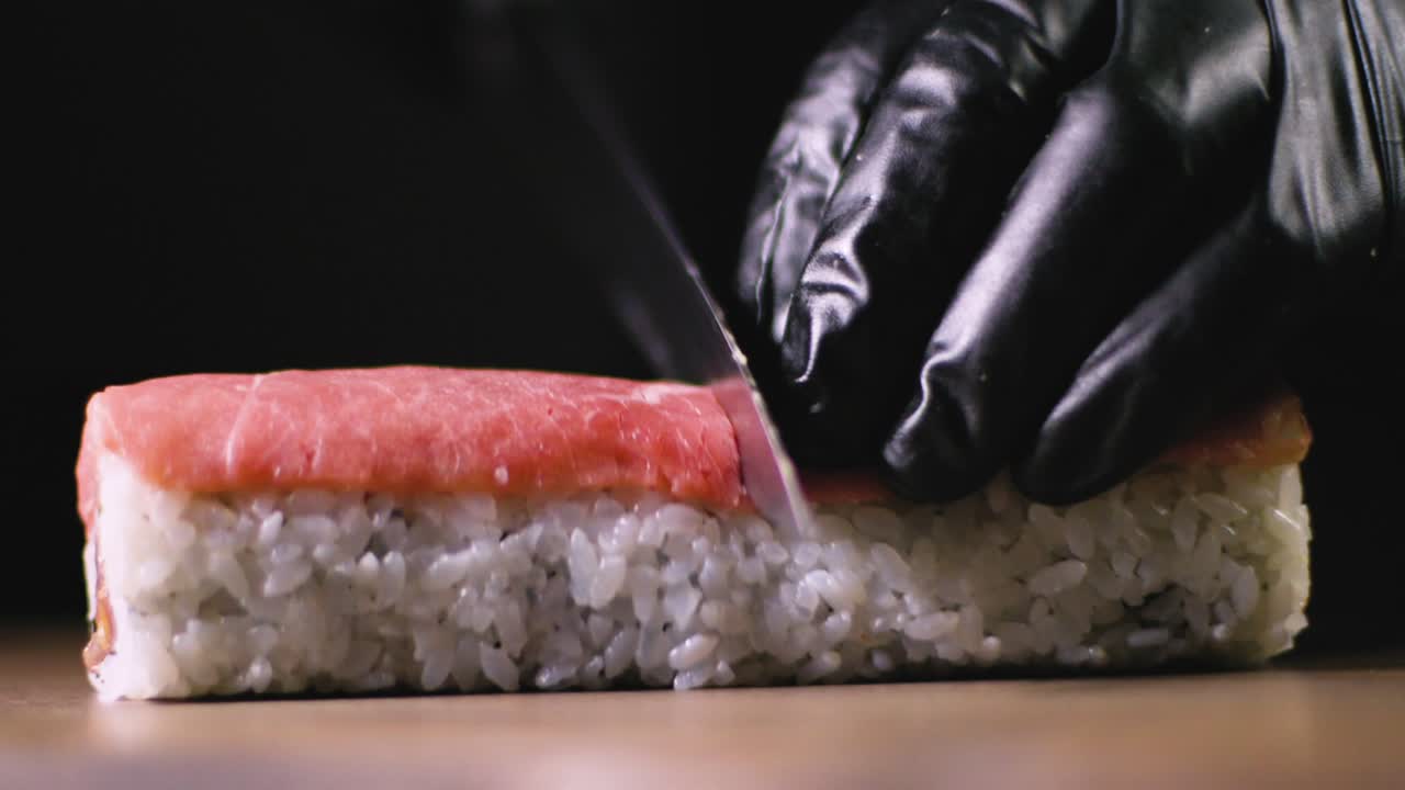 cocinero de cultivos cortando sushi en rollos