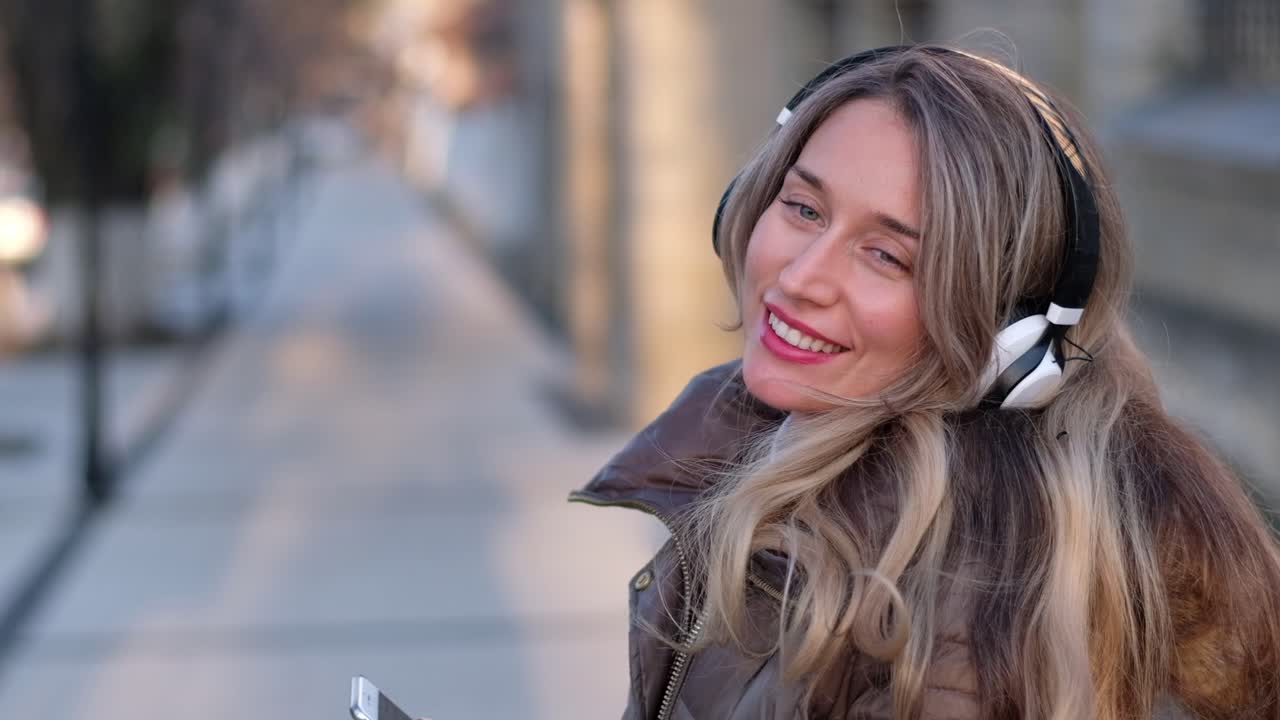 Donna che ascolta la musica con le cuffie mentre canta e balla per strada