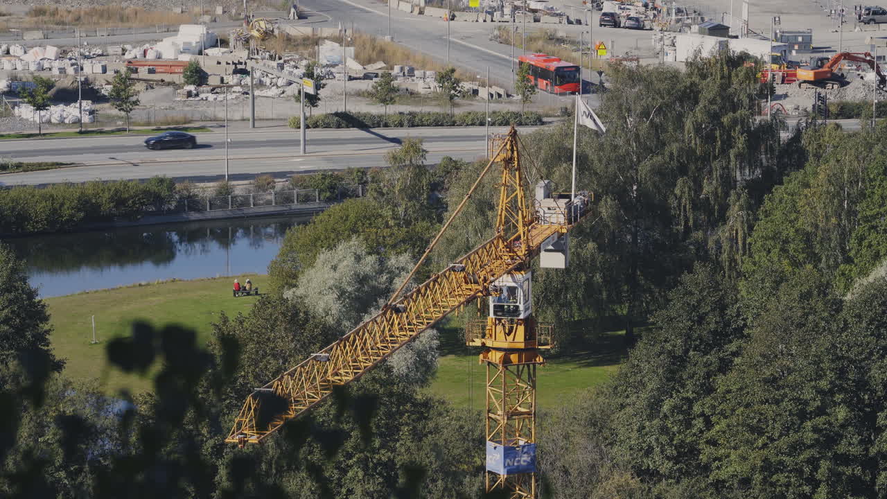 Yellow hoisting crane at construction site, moving and swinging