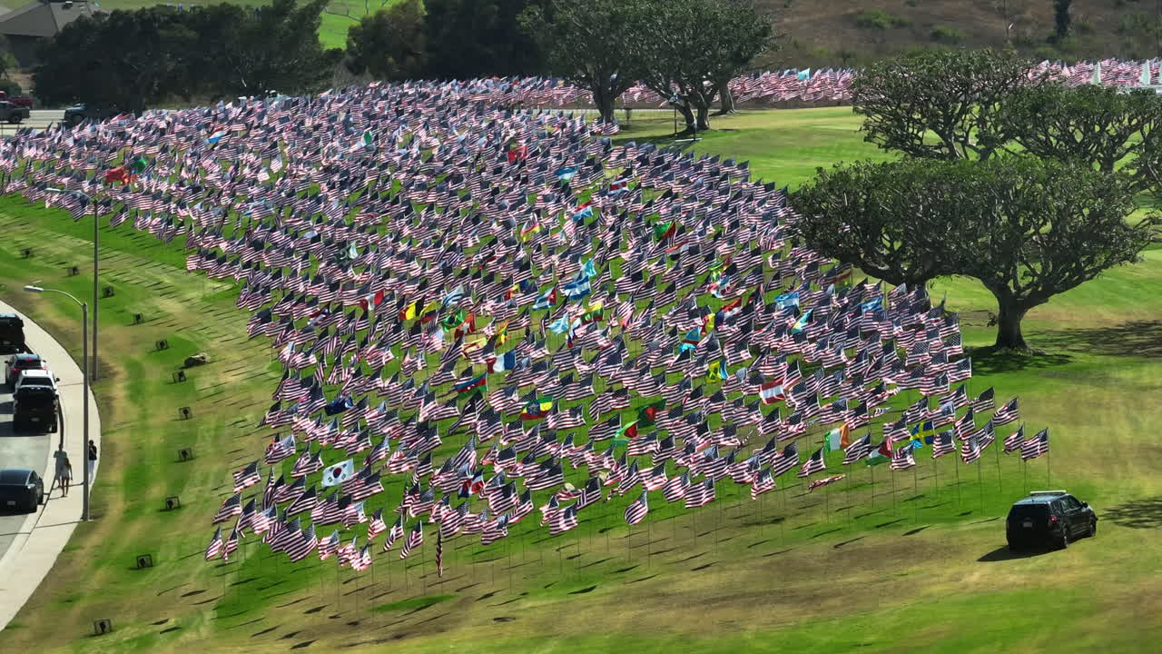 Aerial telezoom around waving US and other flags on a field in California, USA