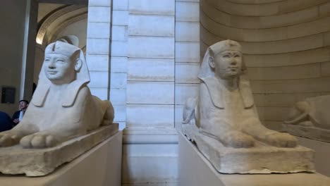 visitors admire ancient sphinx statue in louvre