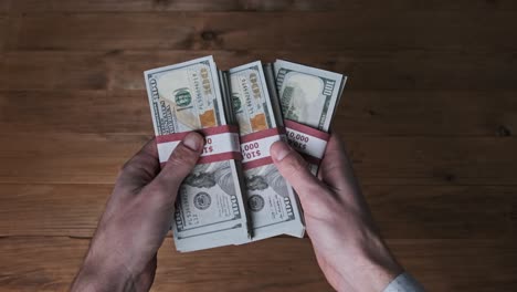 male hands hold three stacks of 10000 us dollar bills and show thumb up sign