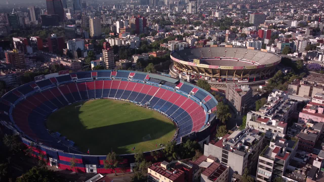 disparo de drones hacia arriba del estadio azul y la plaza de toros ubicados en el sur de la ciudad de méxico al amanecer y rodeados de edificios residenciales