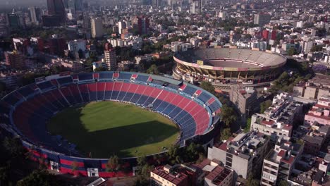 upward drone shot of estadio azul and plaza de toros located in the south of mexico city at sunrise and surrounded by residential buildings