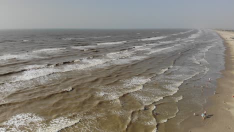 fast pan left past several swimmers, moving towards the waves and stopping over the water