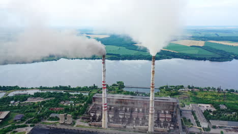 drone shot of industrial zone with thick smog and burning fossil fuels. factory zone pan shot left to right of polluted city, many factory chimneys in city area