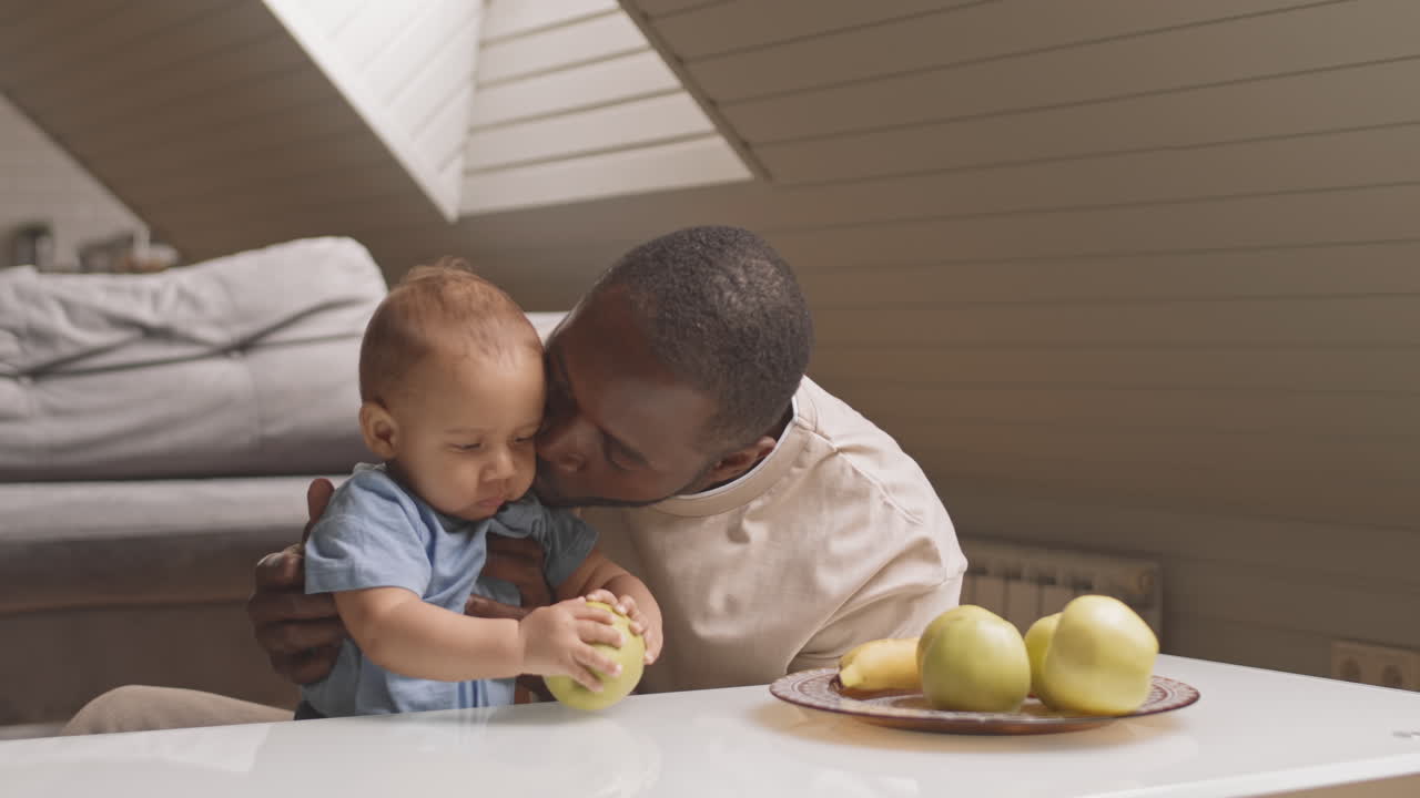 Bebê tentando comer maçã com os pais