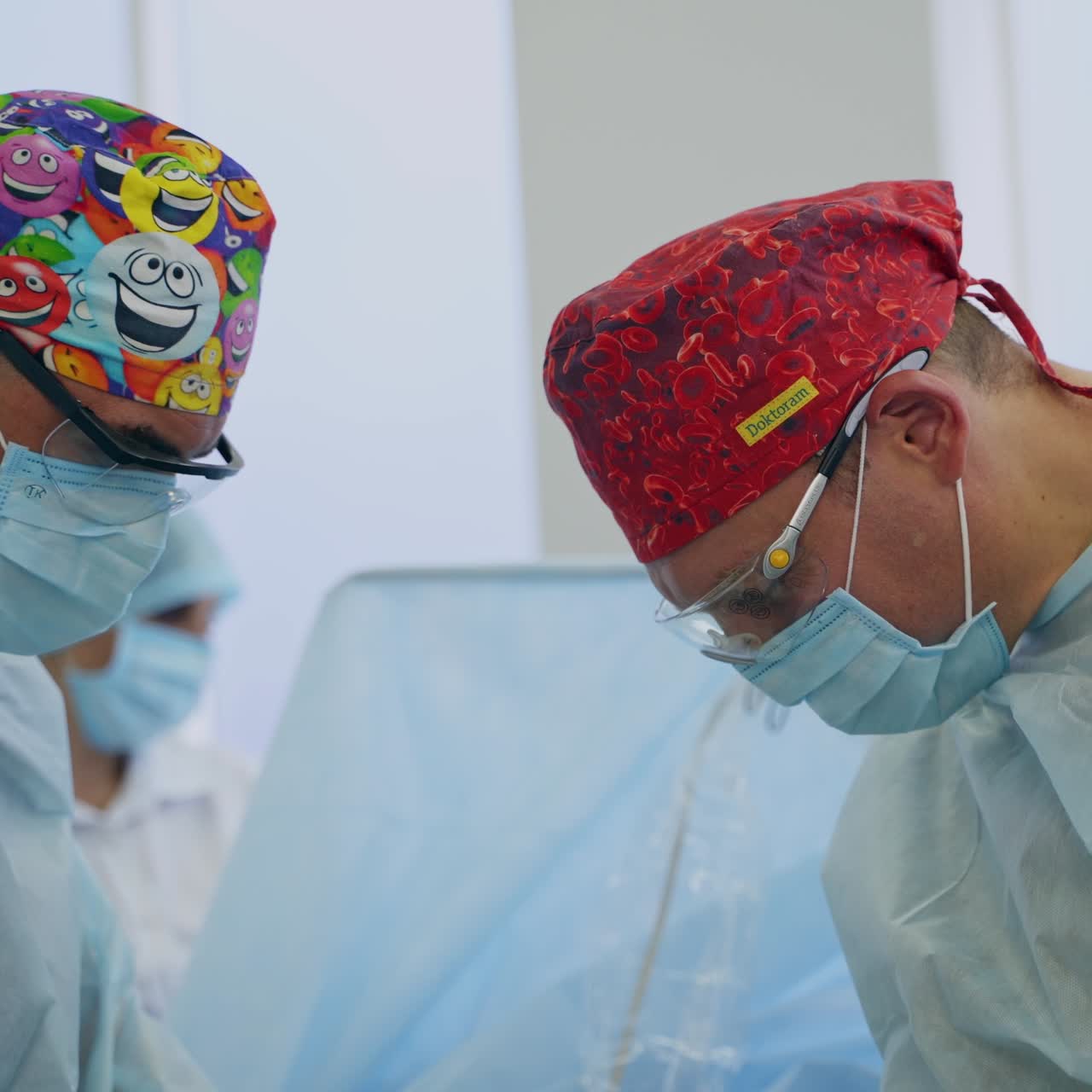 Surgeons in funny caps bent over the patient at surgery. Doctors work hard standing on both sides of a patient