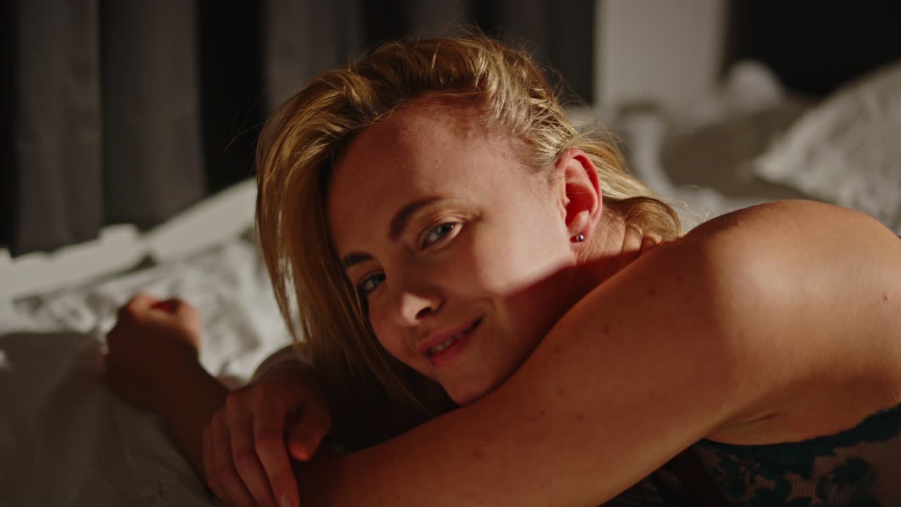 retrato de una mujer bonita en lencería sensualmente acostada en la cama mientras mira a la cámara en cámara lenta