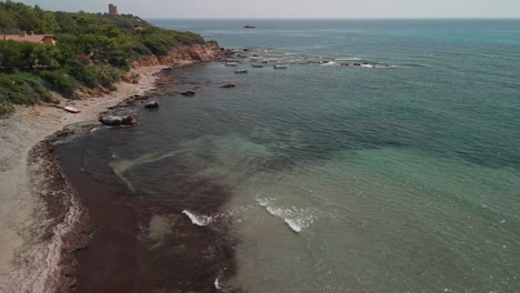 Vista-De-La-Cala-Con-Mar-Transparente-Y-Tranquilo-Cerca-De-La-Costa-Con-Vegetación-Verde-En-Cerdeña,-Italia---Tiro-Estático-Aéreo