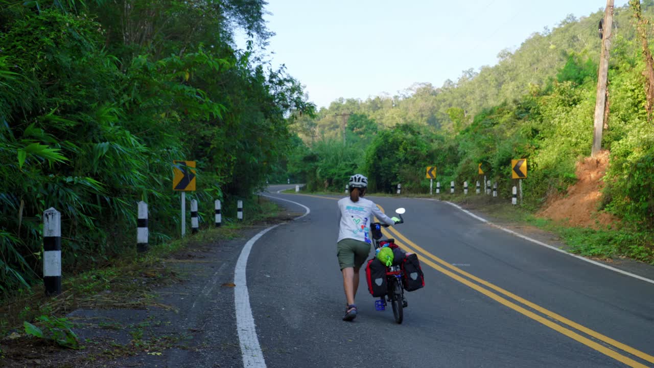 태국 난성 팍 나이 어촌 마을의 숲길에서 자전거를 타고 길을 걷는 여성들의 뒷모습