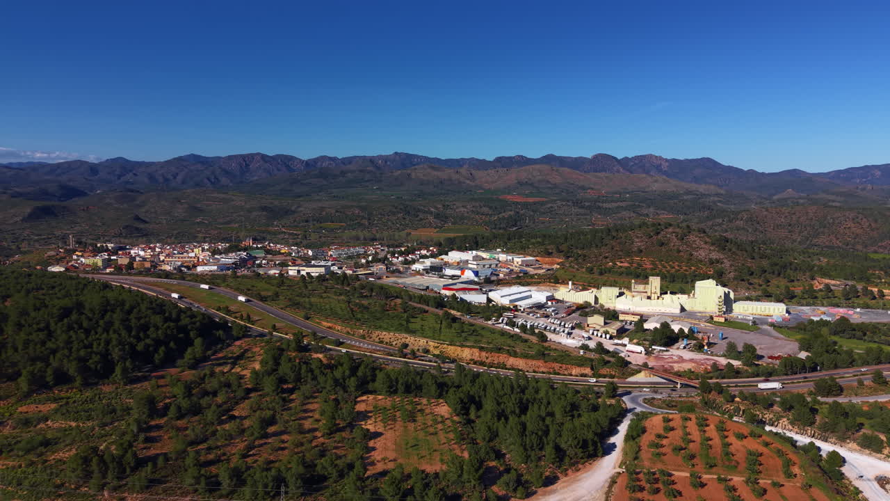 Veduta panoramica di Soneja, Spagna, che mostra una piccola città industriale immersa tra colline boscose e montagne sotto un cielo azzurro e limpido nella regione di Valencia