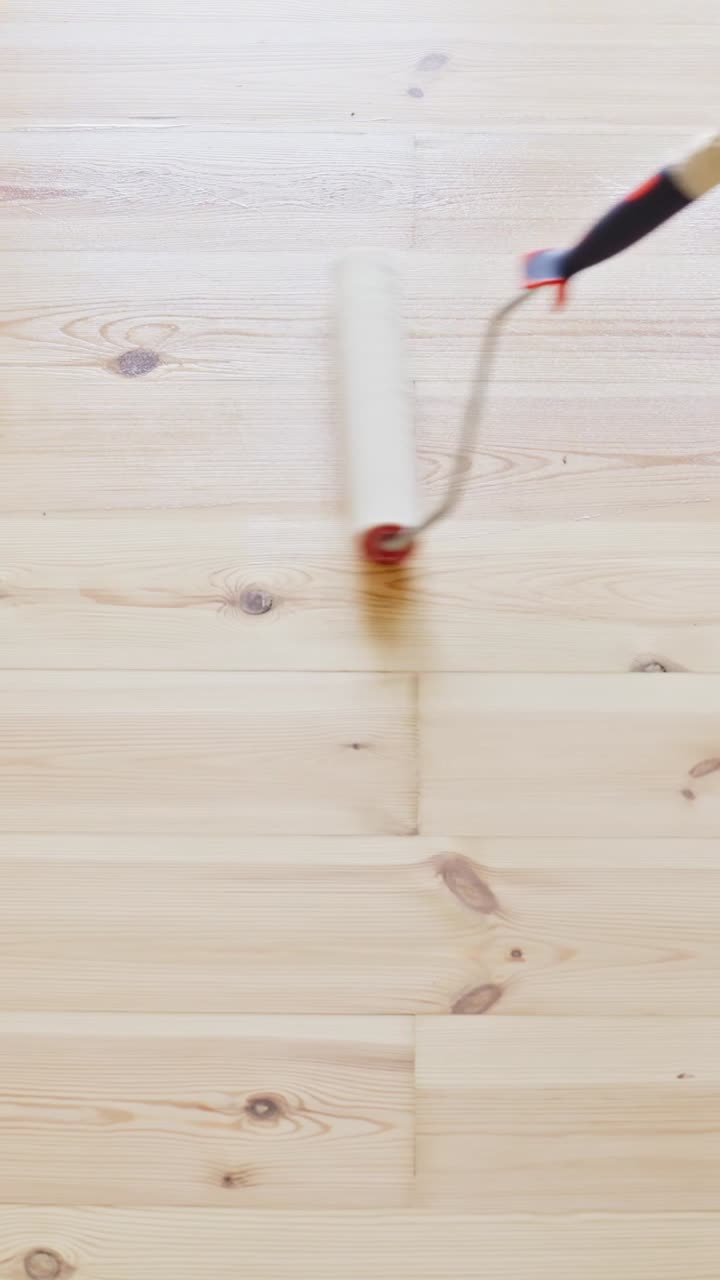 Varnishing hardwood flooring using handheld roller paint brush, static vertical tilted downward