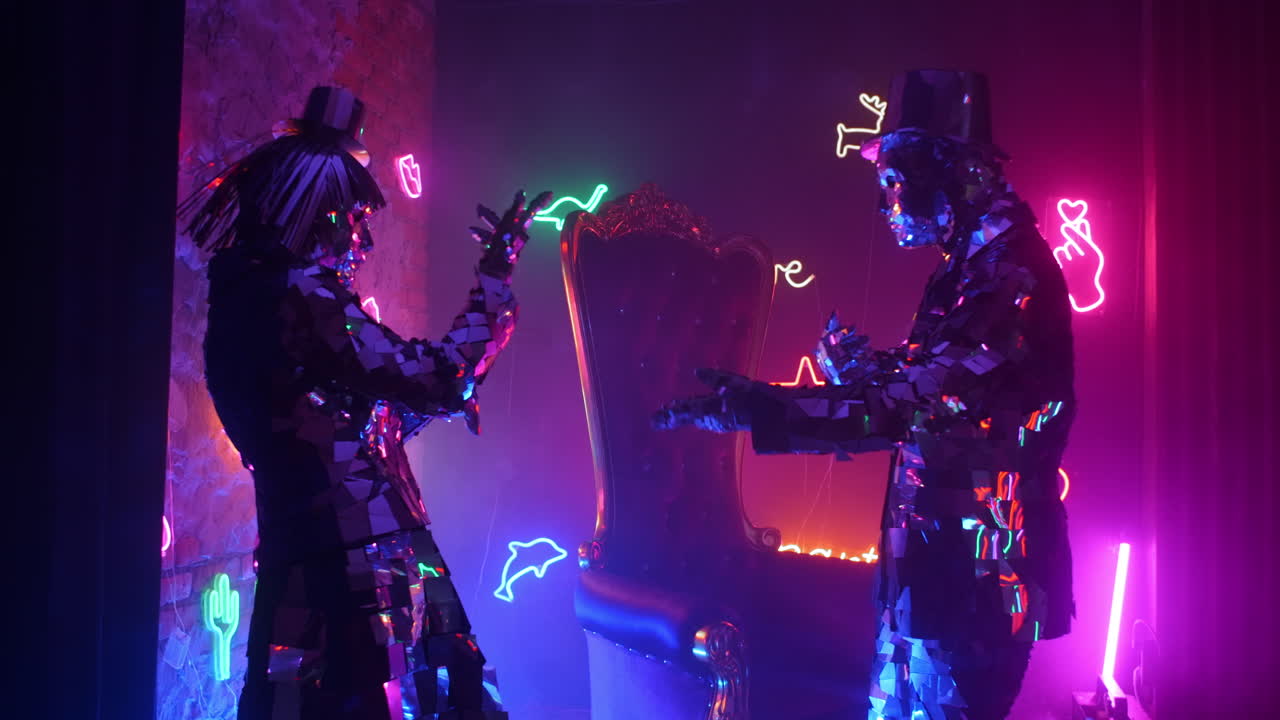 una pareja de diamantes amantes está bailando a la luz de las lámparas ultravioletas de neón. la gente metálica plateada baila el espectáculo de la gente de vidrio.