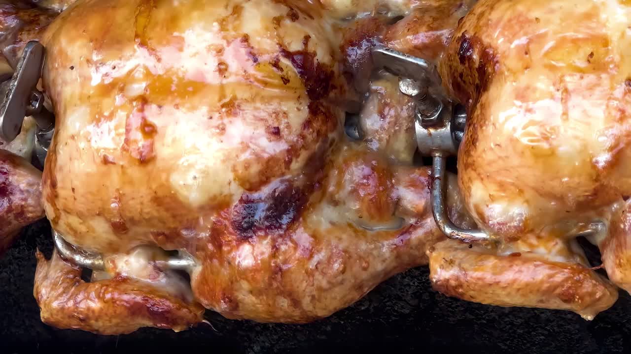 Golden-brown chickens roasting on a rotisserie, showcasing crispy skin and even cooking.
