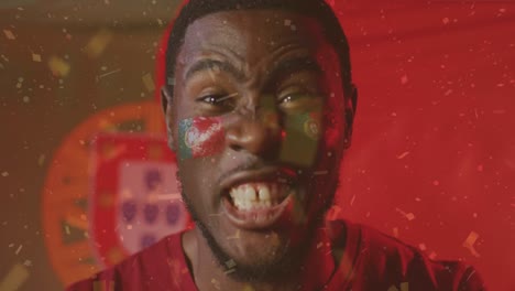 Animation-of-confetti-falling-over-african-american-footballer-celebrating-over-flag-of-portugal